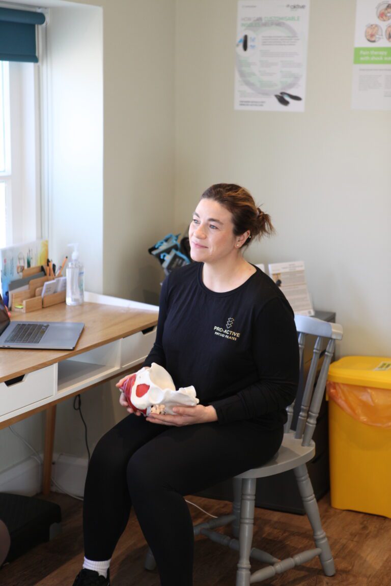 Pelvic health physio holding a model pelvis talking to a patient at pro-active physio pilates